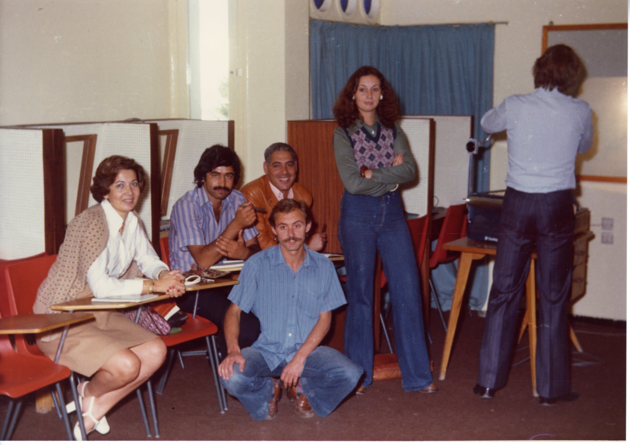 A group of adults posing around desks. 