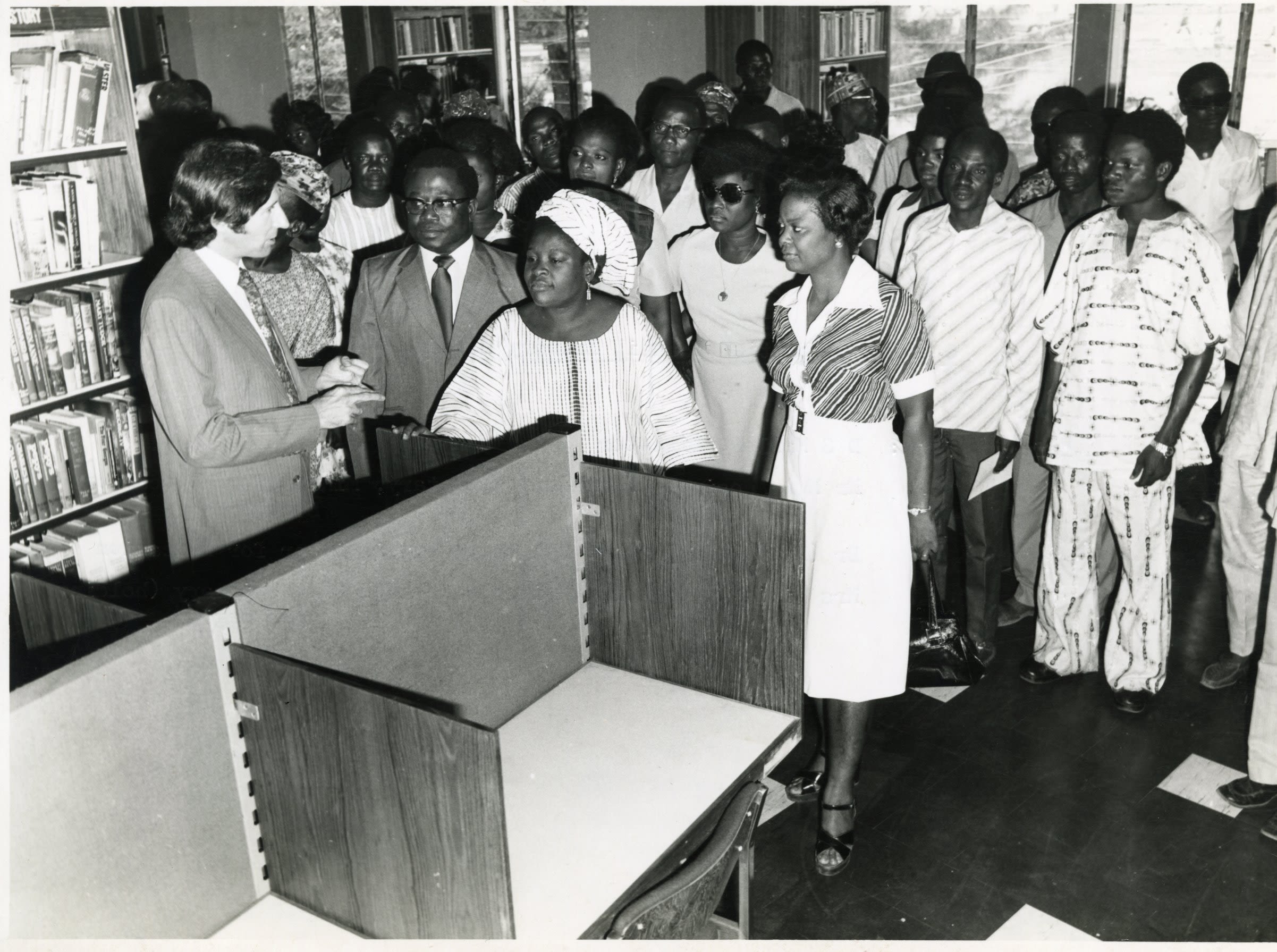 A group of people listening to a man in a library. 