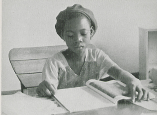 A girl reading a book on a desk.