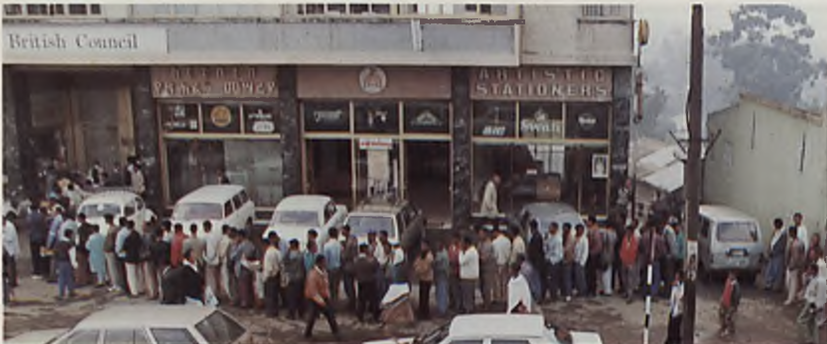 A long queue of people standing on the street outside the British Council library. 