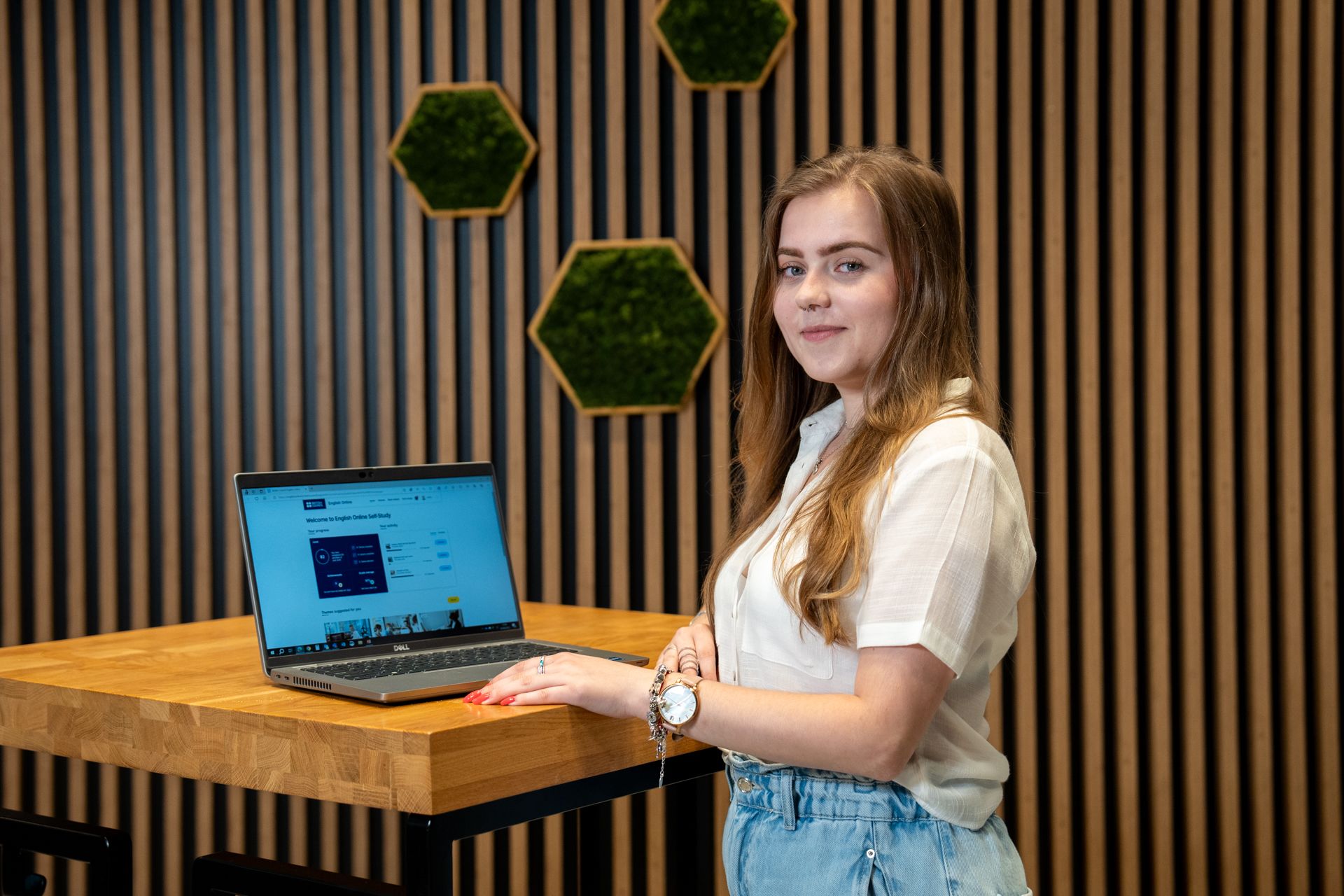 Patrycja at a desk in front of an open laptop.