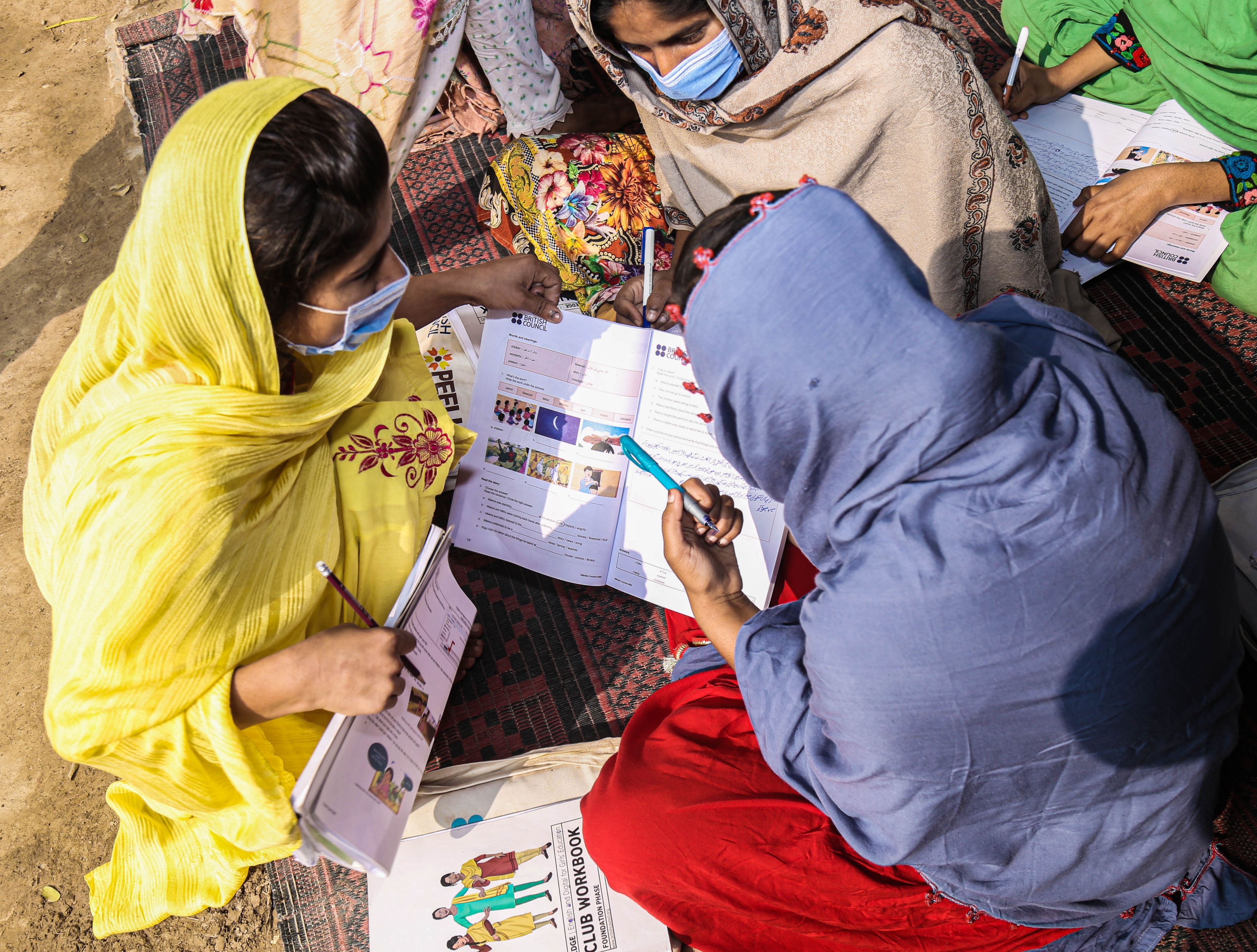 EDGE club members talking with their workbooks open.