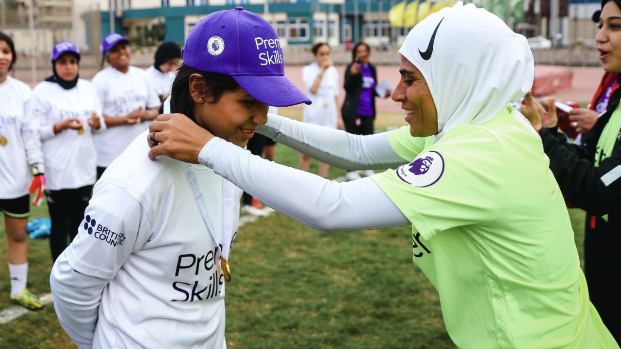 Fayza putting a medal around a Premier Skills participant's neck.